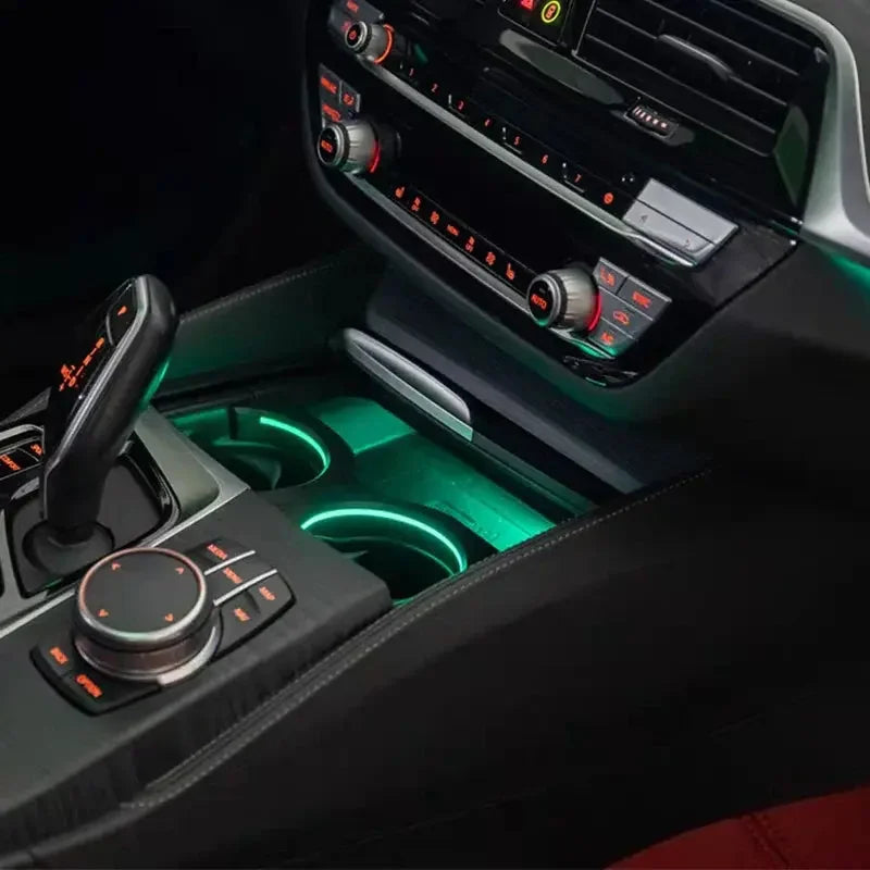 Intérieur de voiture avec console centrale noire, levier de vitesse, éclairage LED vert dans porte-gobelets et commandes climatisation